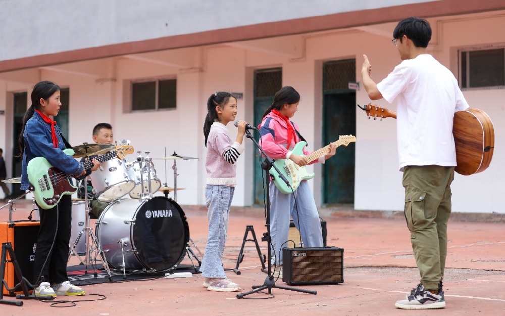 3.2024年5月30日，大巴山深处的巫山县三溪乡田家小学石印村教学点，庄济宇正指导拿云乐队的孩子排练六一演出的曲子。.jpg